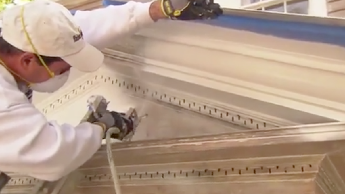 House Painter Spraying Paint On Home.